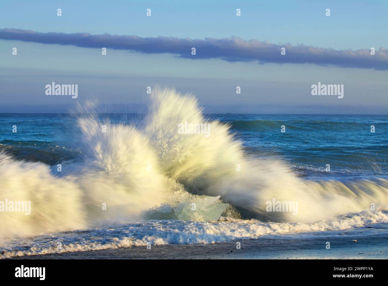 The surf of the Atlantic breaks on blocks of ice washed up on 'Diamond Beach' in the south of Iceland. Stock Photo