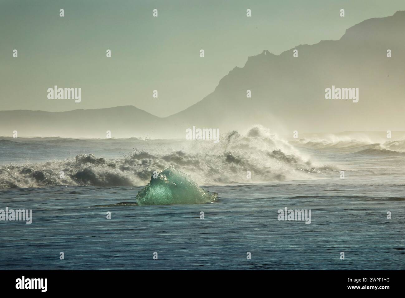 The surf of the Atlantic breaks on blocks of ice washed up on 'Diamond Beach' in the south of Iceland. Stock Photo