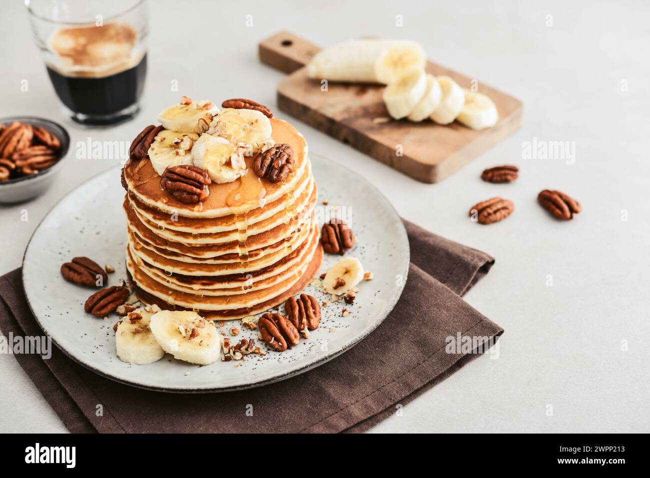 Plate of maple pecan pancakes with fresh bananas and coffee out in the background. Stock Photo
