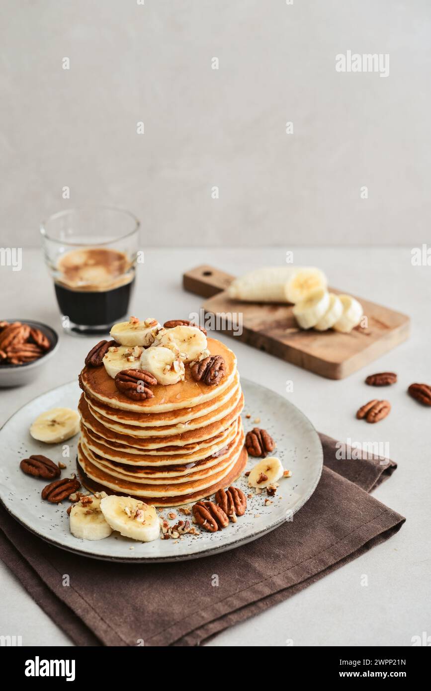Plate of maple pecan pancakes with fresh bananas and coffee out in the background. Stock Photo