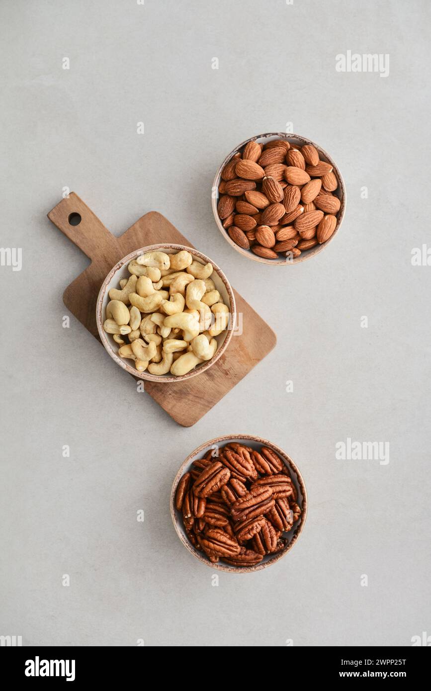 Pecan nuts, almond and cashew in bowls on light background, top view Stock Photo