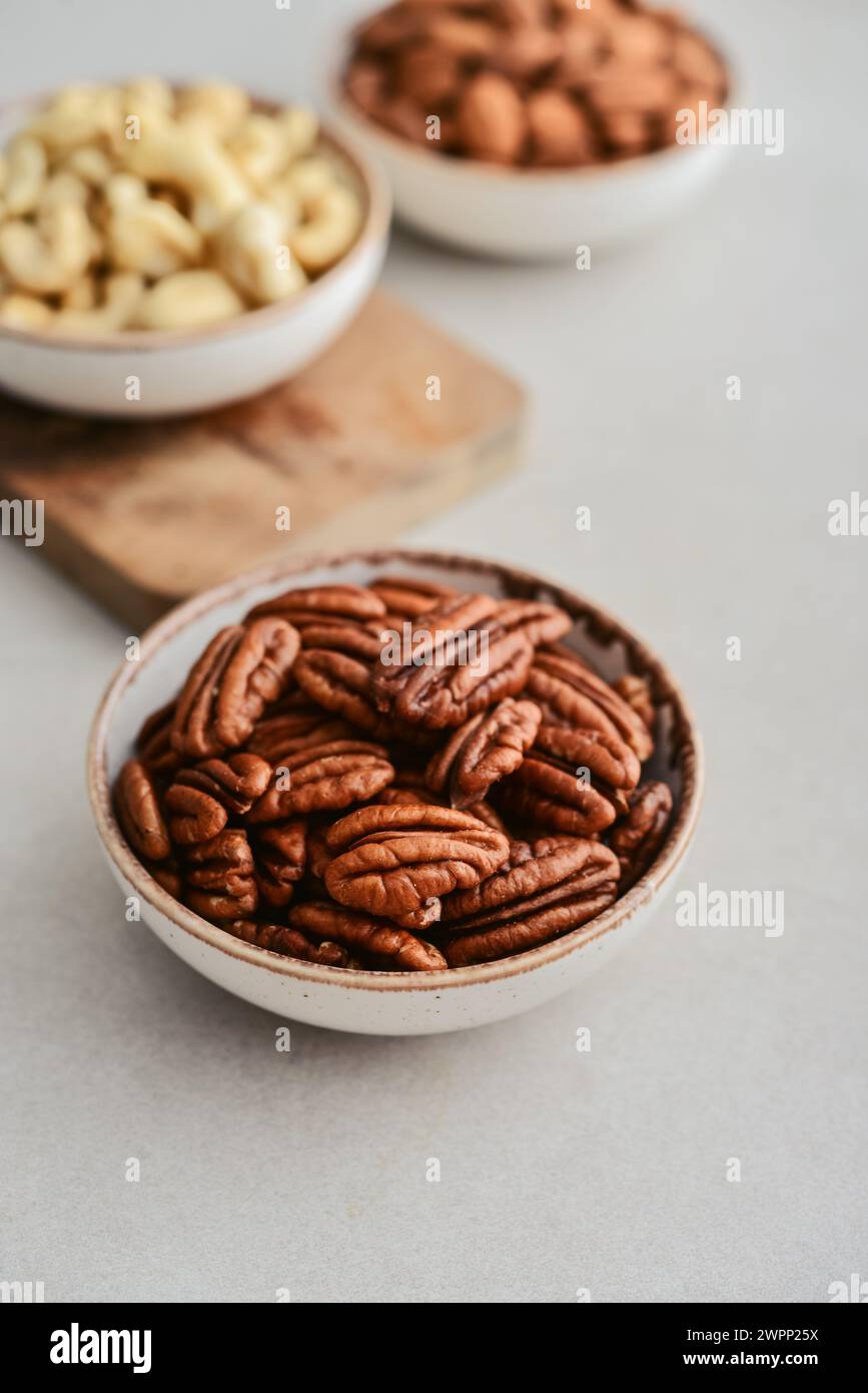 Pecan nuts, almond and cashew in bowls on light background, closeup Stock Photo
