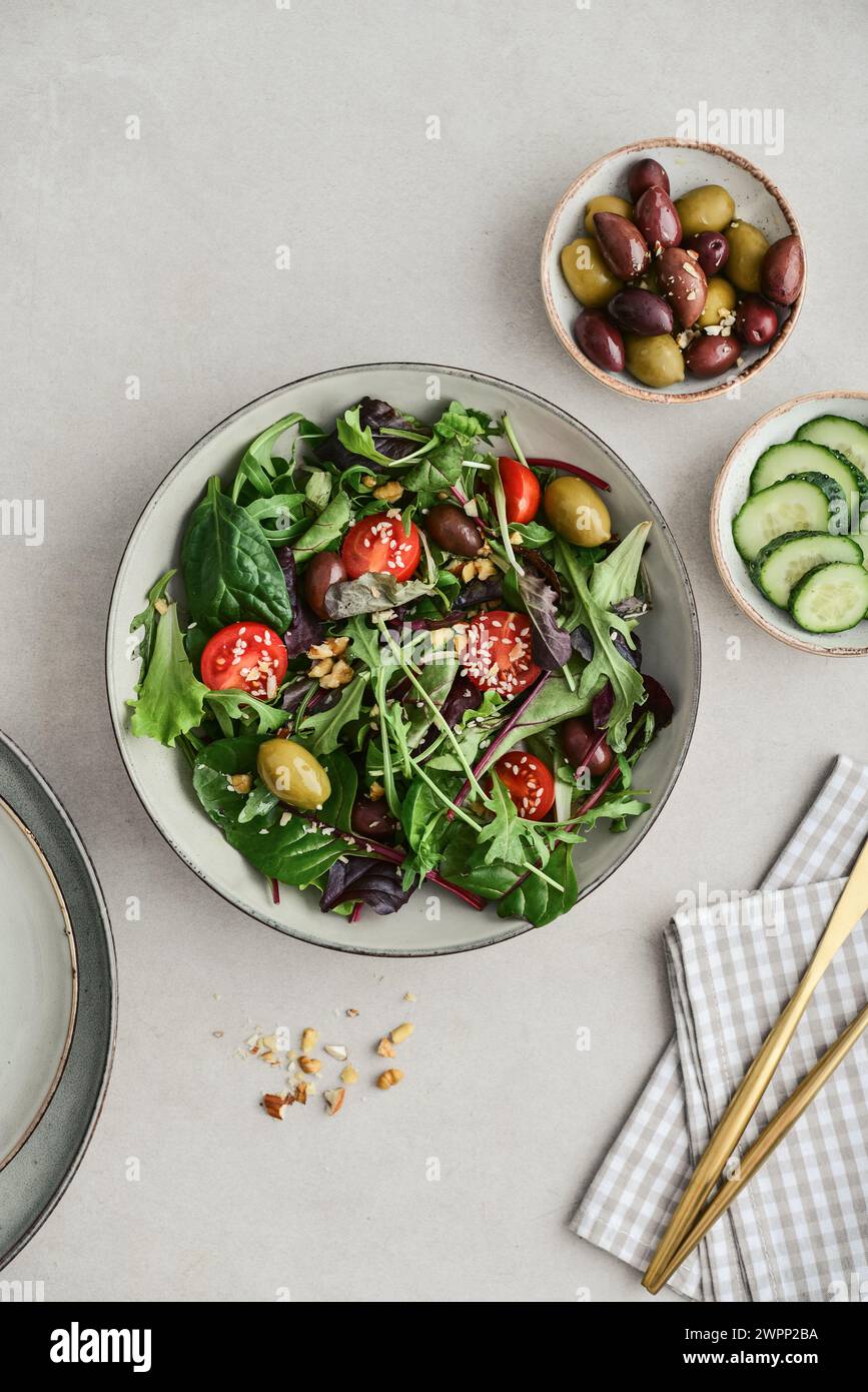 Salad with cherry tomato,  olives, cucumber, arugula, spinach, white and black sesame on plate, top view Stock Photo