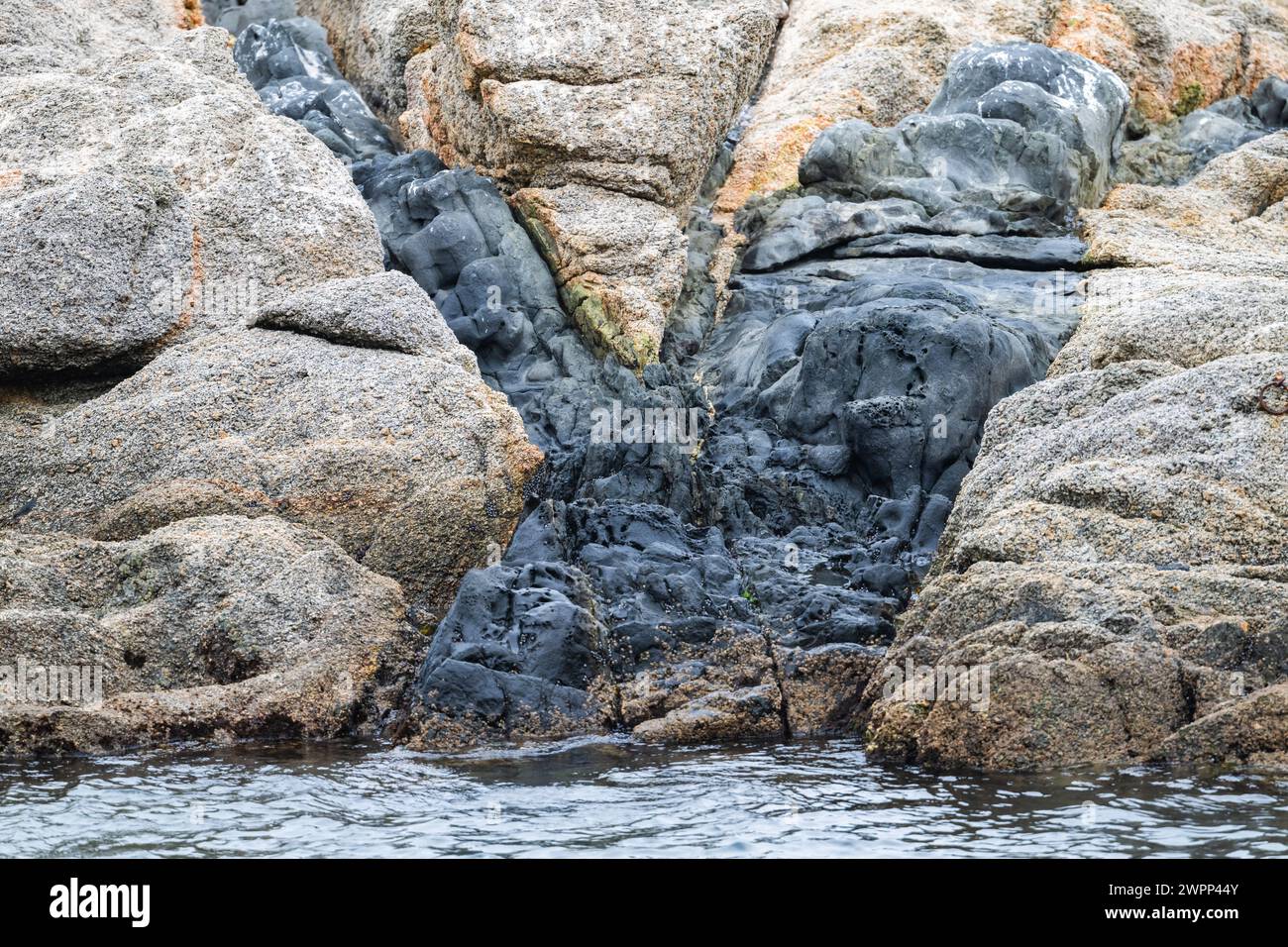 Dark colored igneous rock intruded into older, lighter colored granite. Chile. Stock Photo