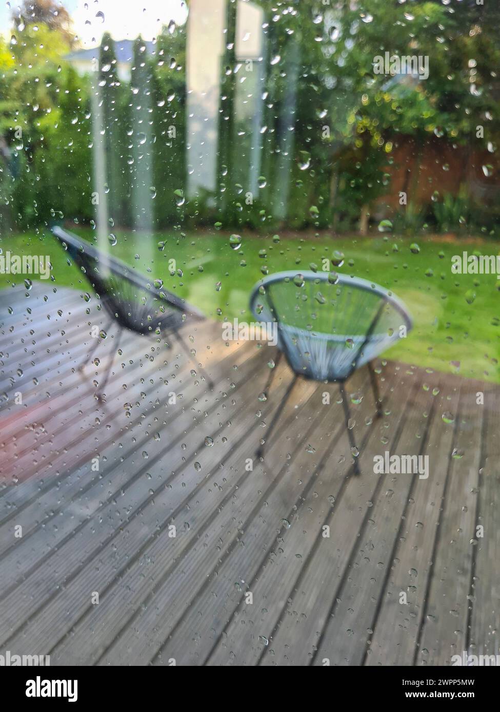 View through the window pane with raindrops onto the wet terrace with ...