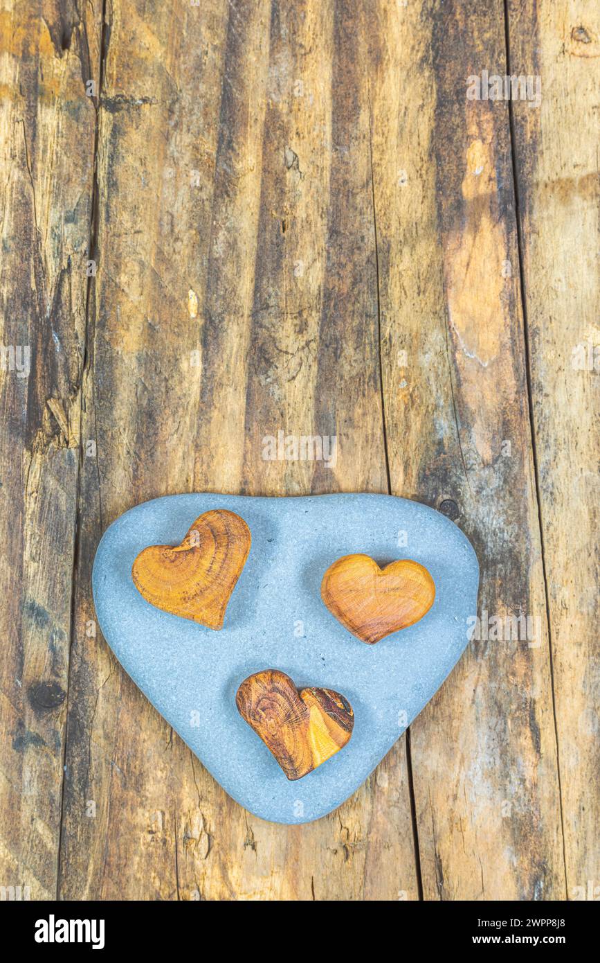 Stone, flotsam and jetsam with 3 wooden hearts Stock Photo