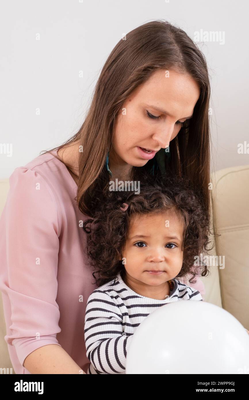 A tender moment between a mother and her mixed-race child a portrait of maternal care and gentle guidance, or child therapy with toys. High quality ph Stock Photo