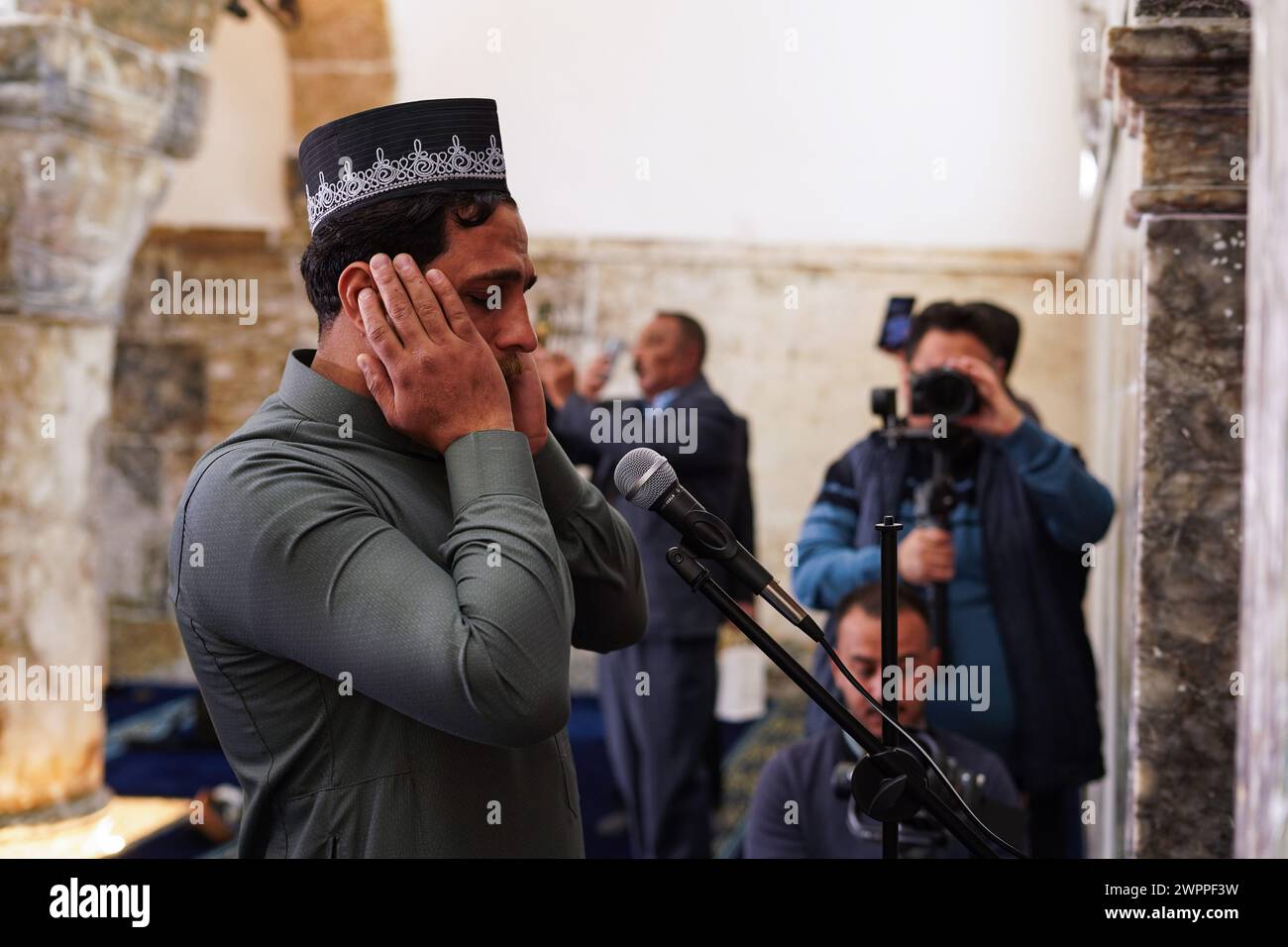 A Muslim performs the noon call to prayer at Al-Masfi (Umayad) mosque in the old city of Mosul after its reopening and completion of its restoration. The Umayad mosque also known Al-Masfi mosque is considered the oldest in Mosul, the second oldest mosque in Iraq, and the 5th oldest mosque in Islam. It dates back to the year 16 AH (637 AD). The mosque was damaged during the operations to liberate the city of Mosul from ISIS, and the mosque was reconstructed by the ALIPH organization in cooperation with LA GUILDE Association and Al-Tameer International Group, in cooperation with the Sunni Endowm Stock Photo