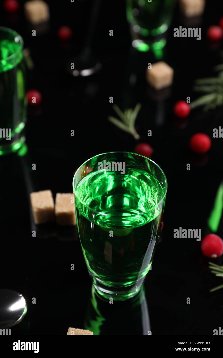 Absinthe in shot glass on mirror table, closeup. Alcoholic drink Stock Photo
