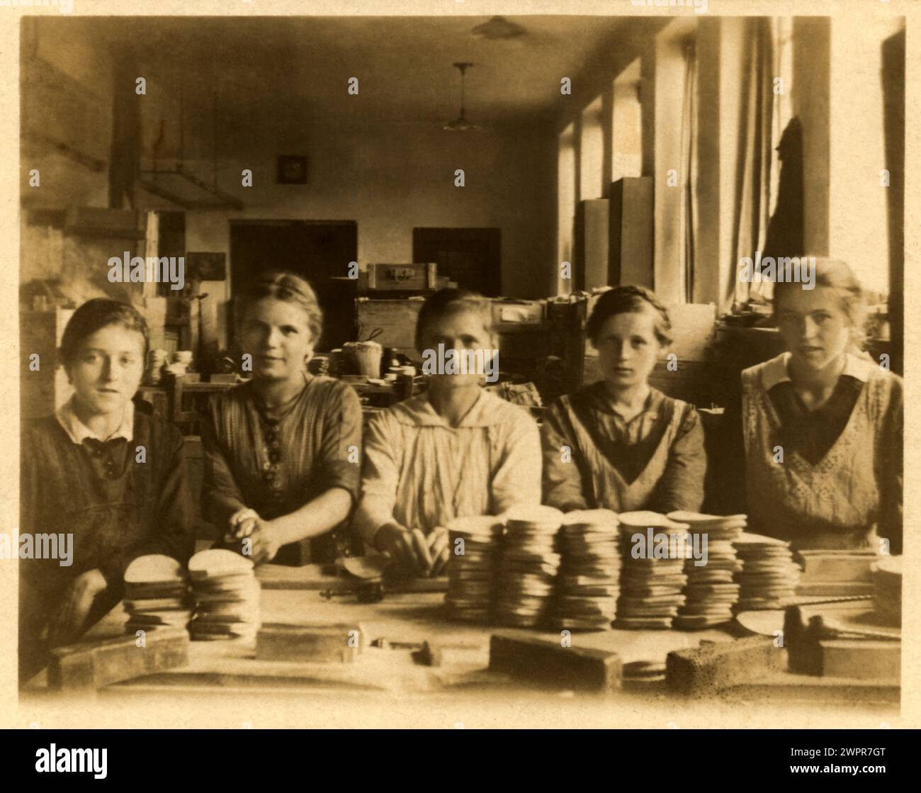 1918 c. , GERMANY : image taken inside a workshop in which five girl workers are portrayed in front of their manufactured products ( it is not possible to understand whether they are felt circles components of some electric battery or for other mechanical or automotive use or for shoe soles ). Photo by unknown unprofessional photographer . - GERMANIA  - FOTO STORICHE - HISTORY  - EMANCIPAZIONE FEMMINILE - FEMMINISMO - LIBERAZIONE DELLA DONNA -  WOMEN'S EMANCIPATION - FEMINISM - WOMEN'S LIBERATION - OPIFICIO - OFFICINA - MANODOPERA - ANNI DIECI - 1910's - 10's - '10  - RAGAZZE - RAGAZZA - DONNA Stock Photo