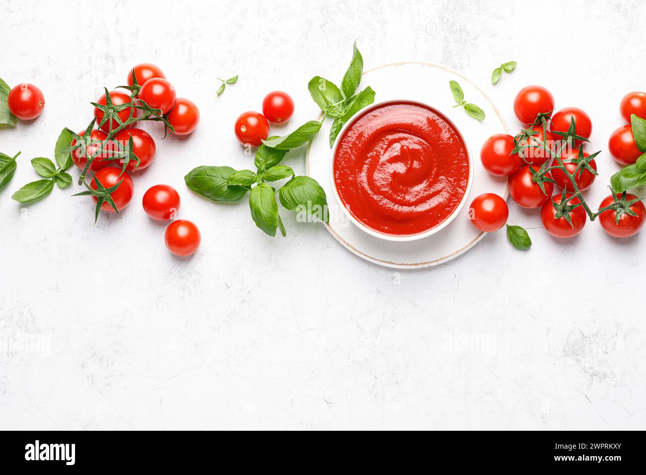 Tomato paste, sauce, ketchup and cherry tomatoes on branches and basil with copy space on white background, top view Stock Photo