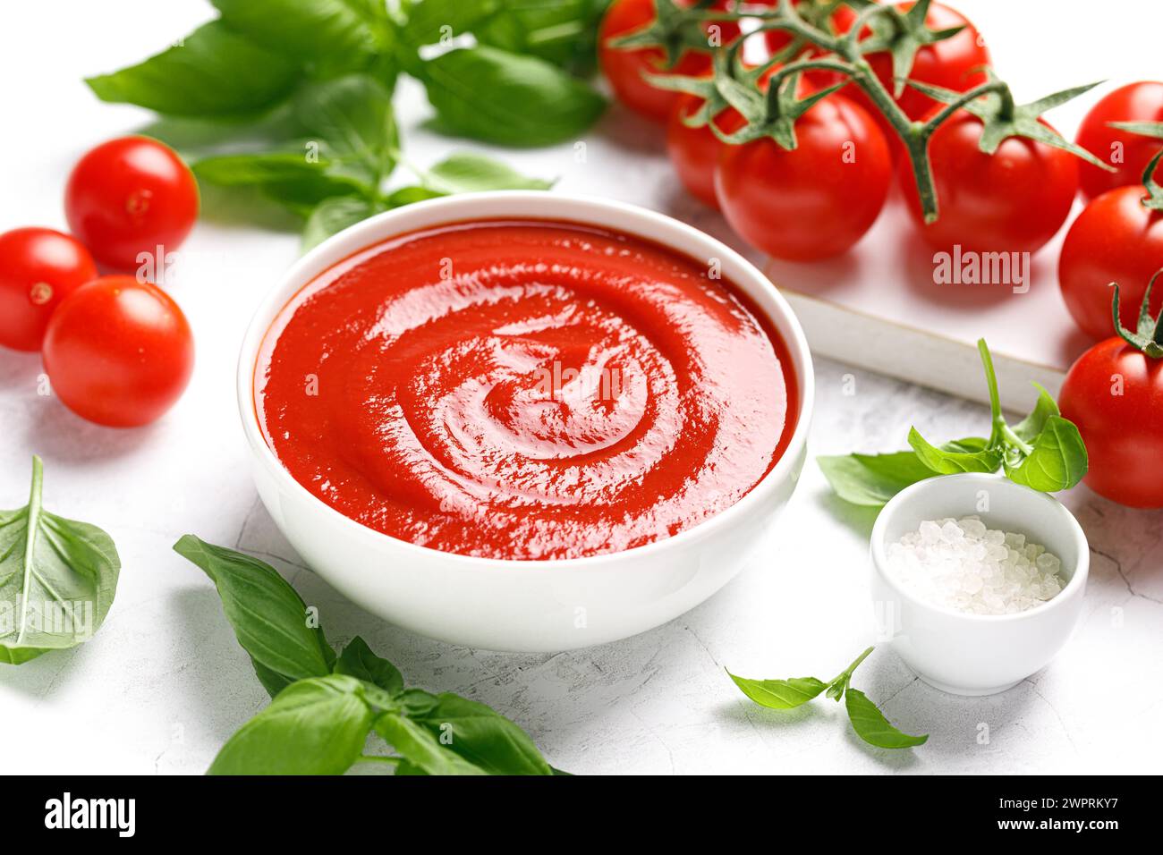 Tomato paste, sauce, ketchup and cherry tomatoes on branches and basil with copy space on white background Stock Photo