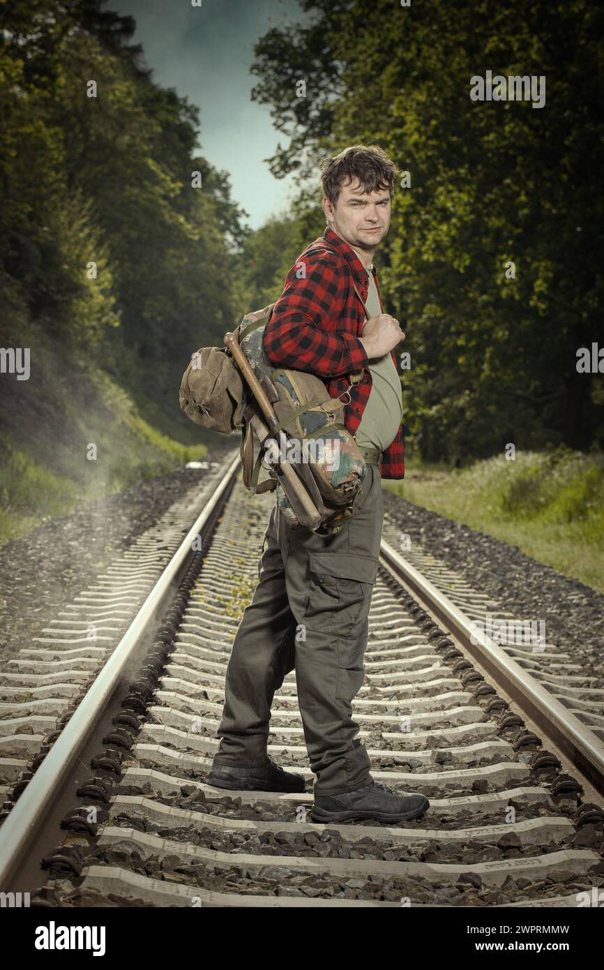 Adventurer with retro haversack wandering nature on railroad way Stock Photo