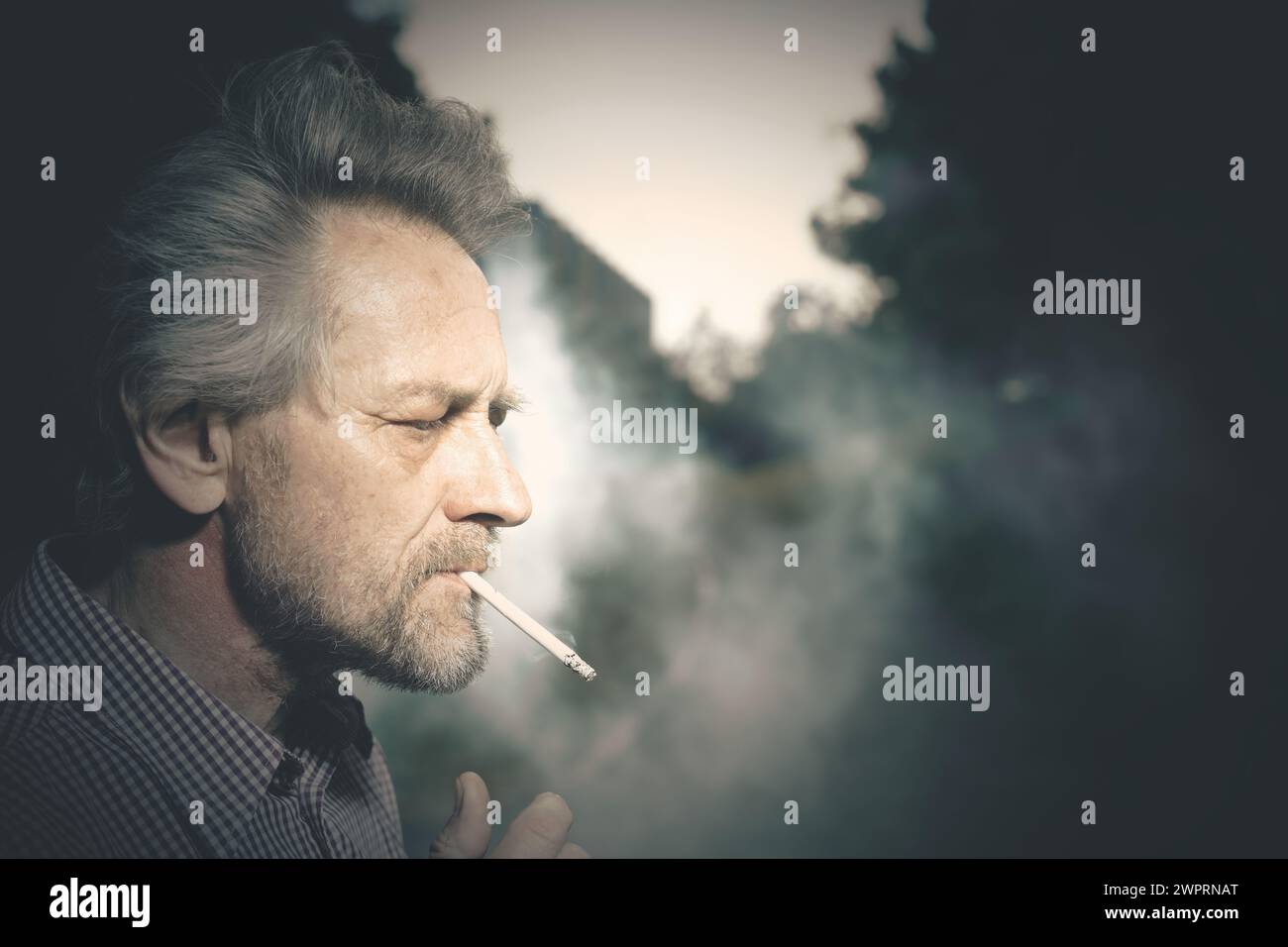 Aged man smoking cigarettes in city park lately on day time Stock Photo