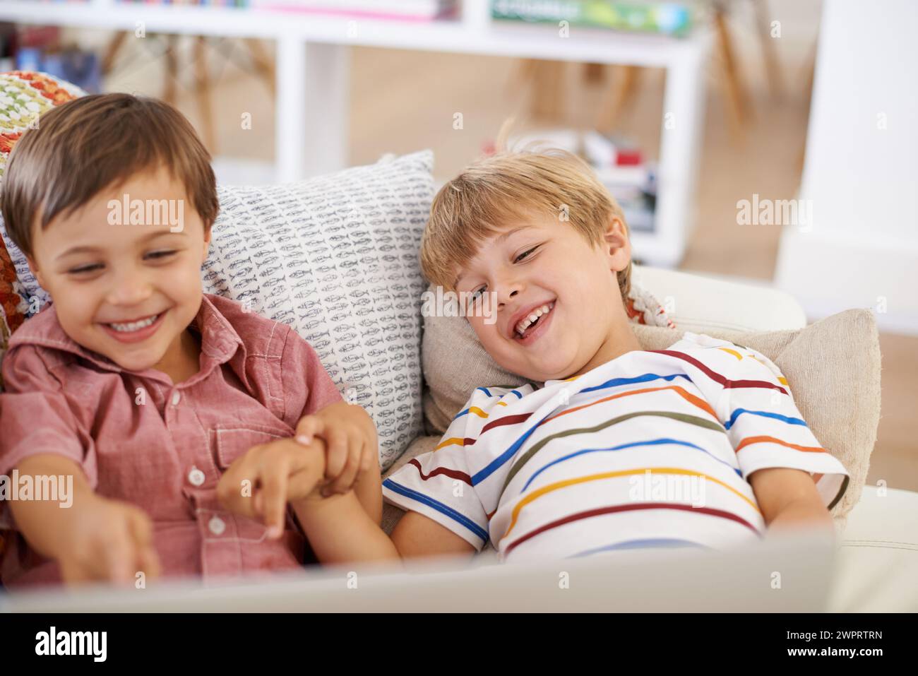 Laptop, kids and happy siblings on sofa for cartoon, film or streaming funny movie at home. Computer, learning or boy children in house for google it Stock Photo