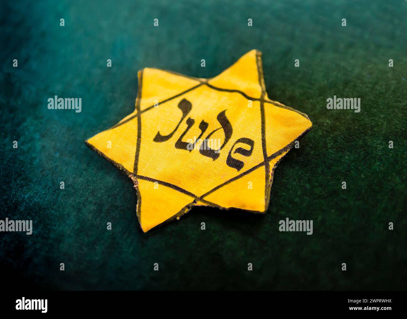 Yellow Star of David outlined in black with the German word for 'Jew' written in Hebrew style on canvas, used by the Nazis during the Holocaust to ide Stock Photo