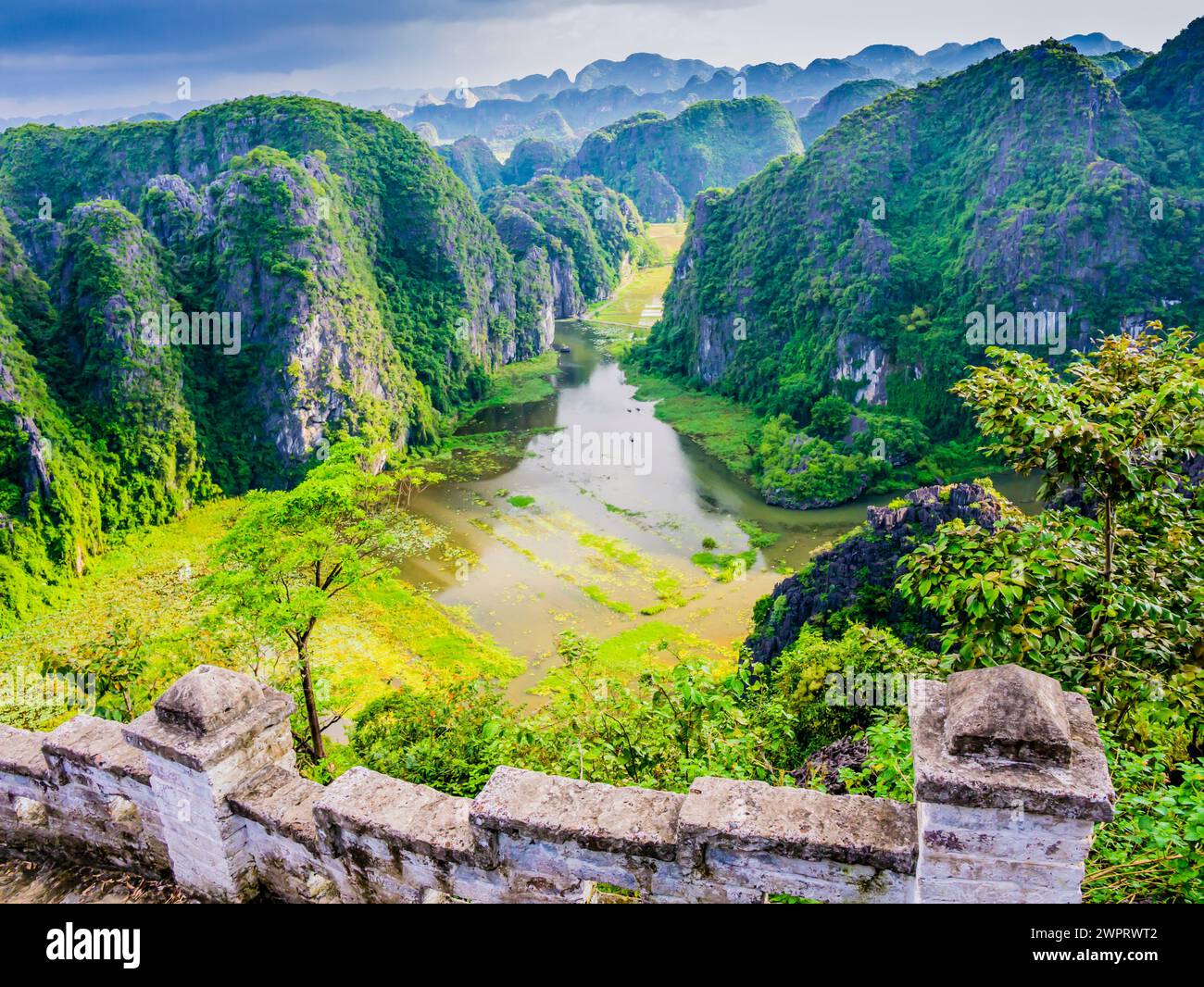 Impressive karst formations and rice paddy fields in Tam Coc with the stone staircase ascending the lying dragon in foreground, Ninh Binh province, Vi Stock Photo