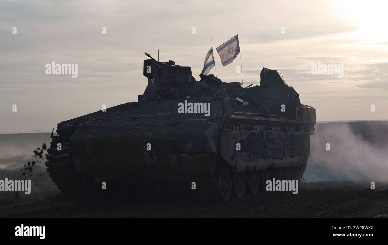 Israeli military armored vehicles return from central Gaza amid continuing battles between Israel and the militant group Hamas on March 7, 2024 in Gaza border, southern Israel. Stock Photo