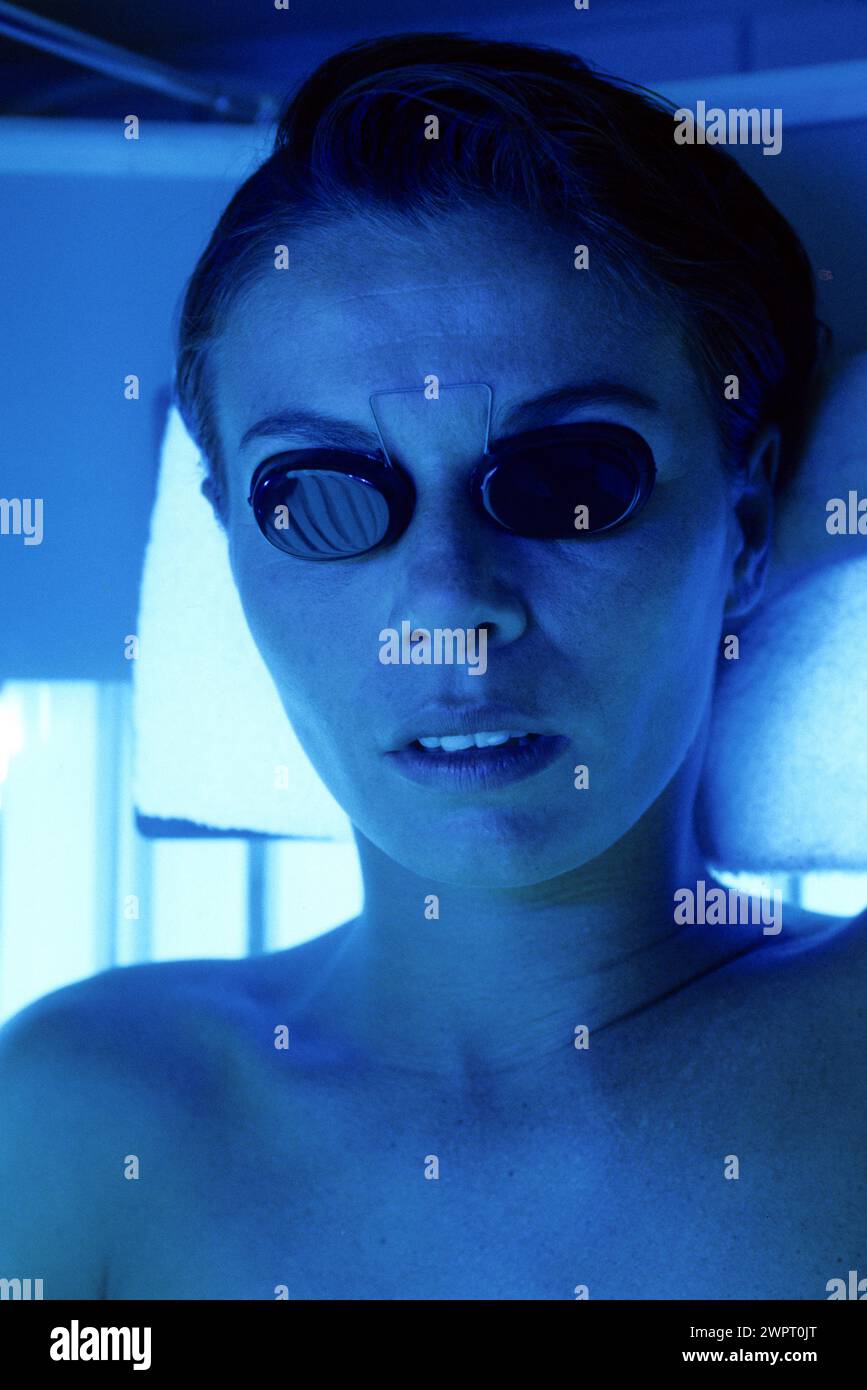 young woman portrait alternative medecine UV cabin close up face with little sunglasses to protect eyes Stock Photo