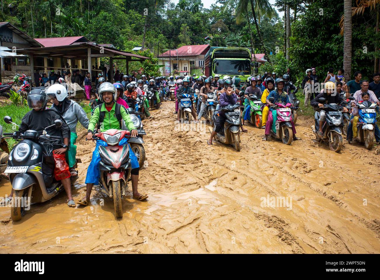 West Sumatra, Indonesia. 9th Mar, 2024. People ride motorbikes on a muddy road after heavy rains in Pesisir Selatan in West Sumatra, Indonesia, March 9, 2024. Credit: Andri Mardiansyah/Xinhua/Alamy Live News Stock Photo