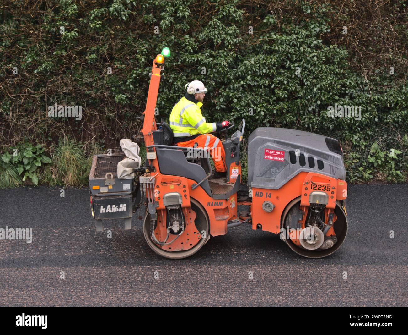 A worker driving a road roller compactor during Road resurfacing work, UK Stock Photo