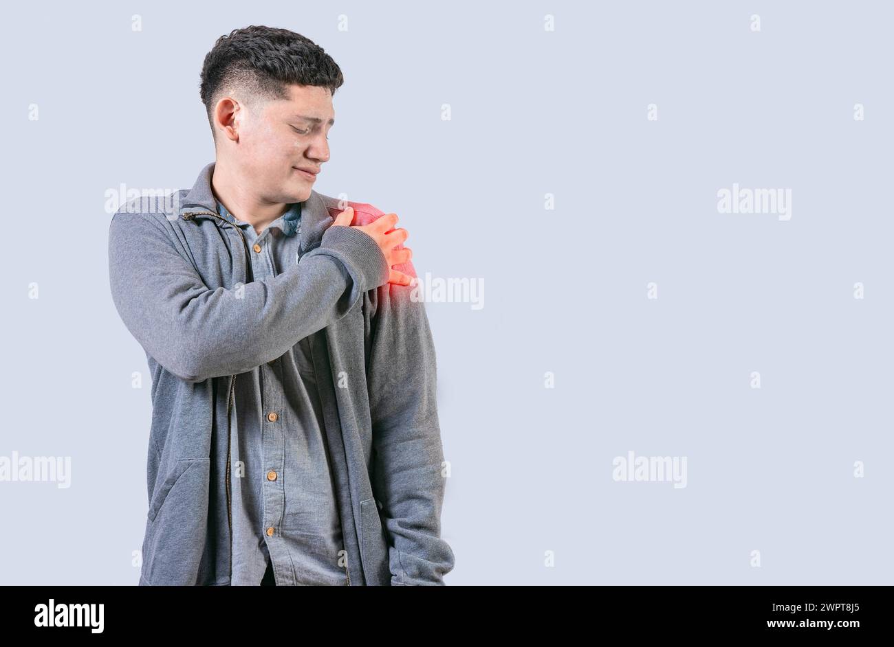 Person in pain holding his shoulder isolated. Youg man suffering with arms pain isolated Stock