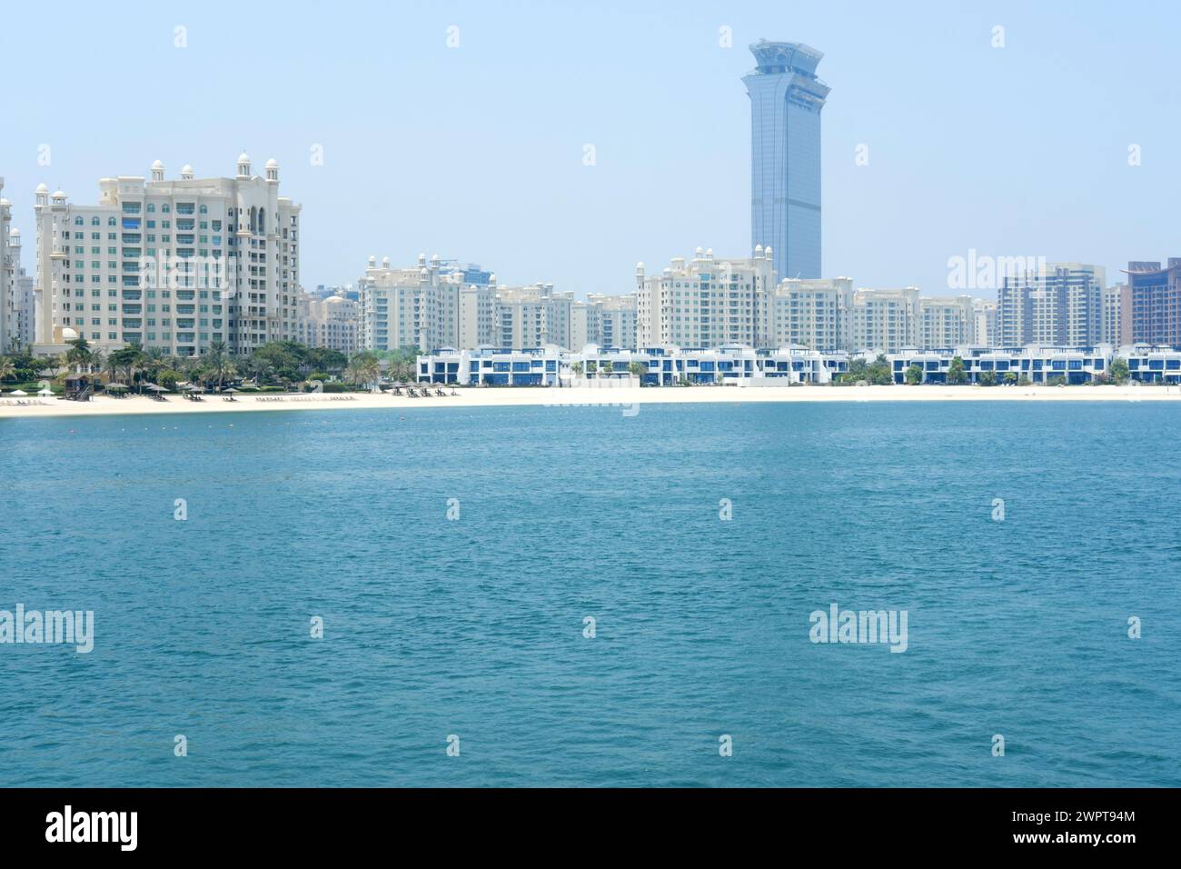 Coastal view showcasing a contrast of modern beachside resorts and the iconic tower against the azure waters of Dubai. Dubai, UAE - August 15, 2023 Stock Photo
