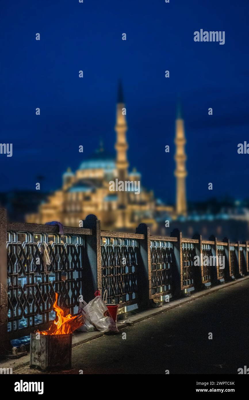 Early morning and a fisherman's fire with the New Mosque (Yeni Cami) in Istanbul, Turkey Stock Photo