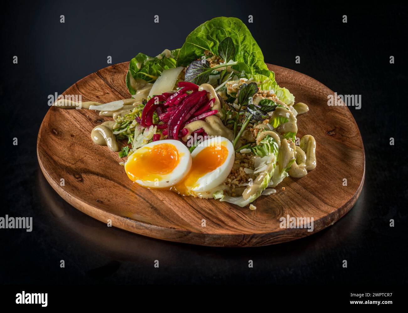 Salad on wooden plate with soft boiled egg Stock Photo