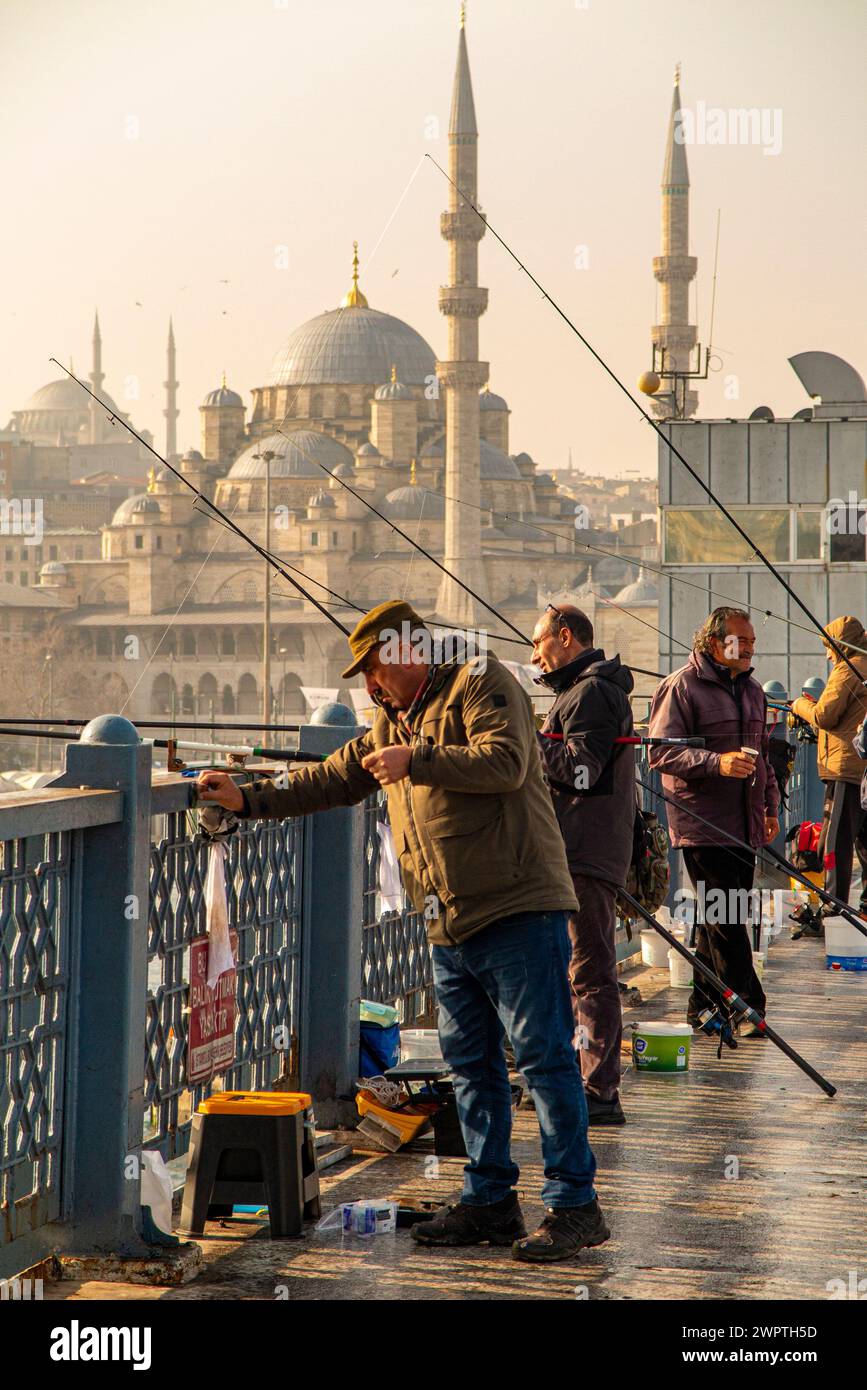 Fishermen at dawn on Galata Bridge inIstanbul, Turkey,with the New Mosque in the background Stock Photo