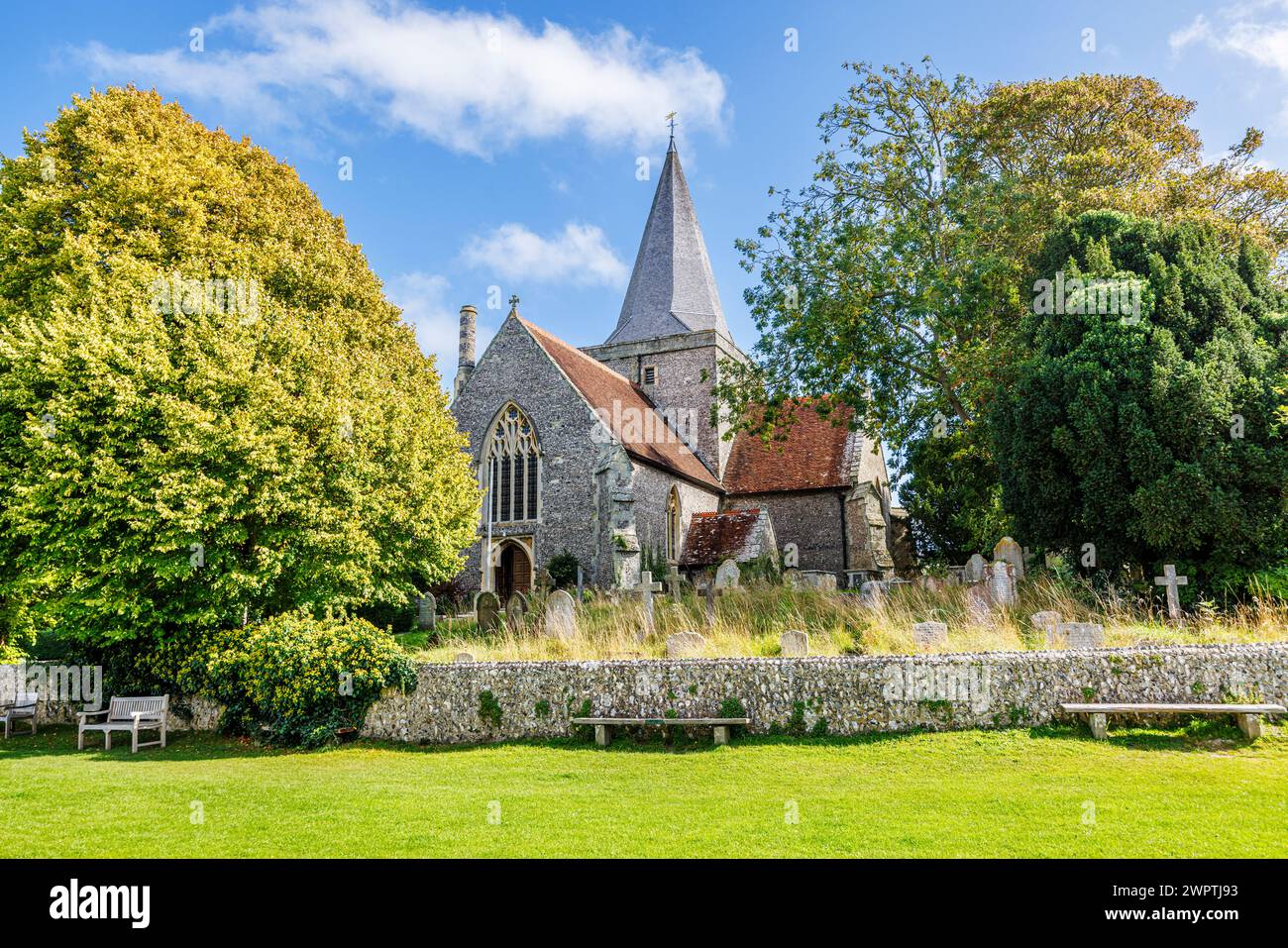 The Church of St Andrew and overgrown churchyard in Alfriston, a pretty historic village in the Wealden district of East Sussex Stock Photo