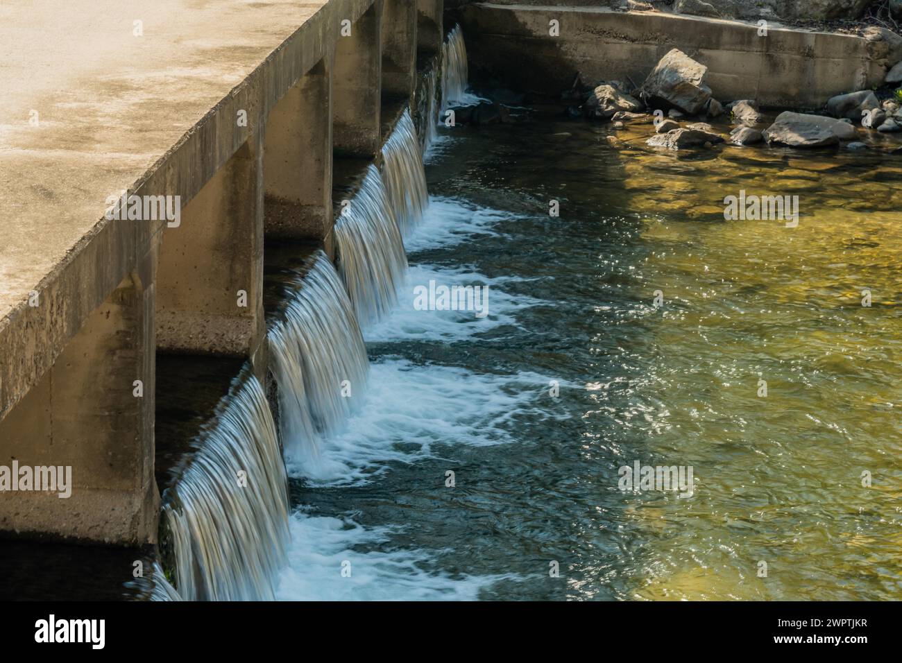 Water flowing smoothly over a concrete dam spillway, in South Korea