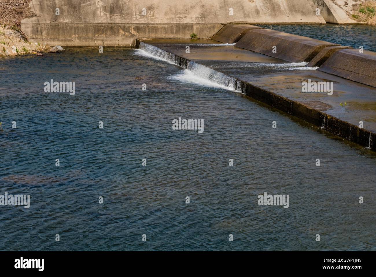 Bright daylight captures water flowing smoothly over a concrete