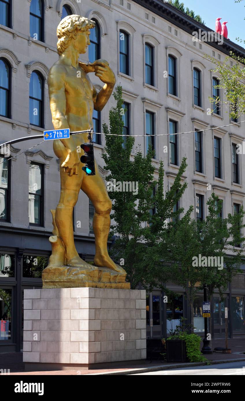 A large, golden reproduction of Michelangelo's David sculpture by Turkish artist Serkan Özkaya stands on a corner in downtown Louisville, Kentucky. Stock Photo