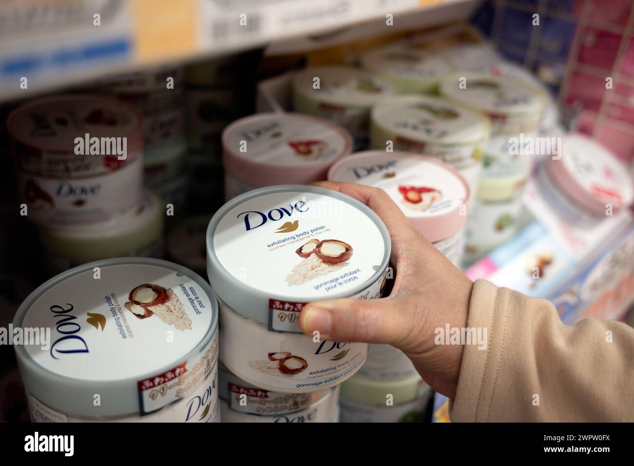 A hand getting a container of Dove exfoliating lotion Stock Photo