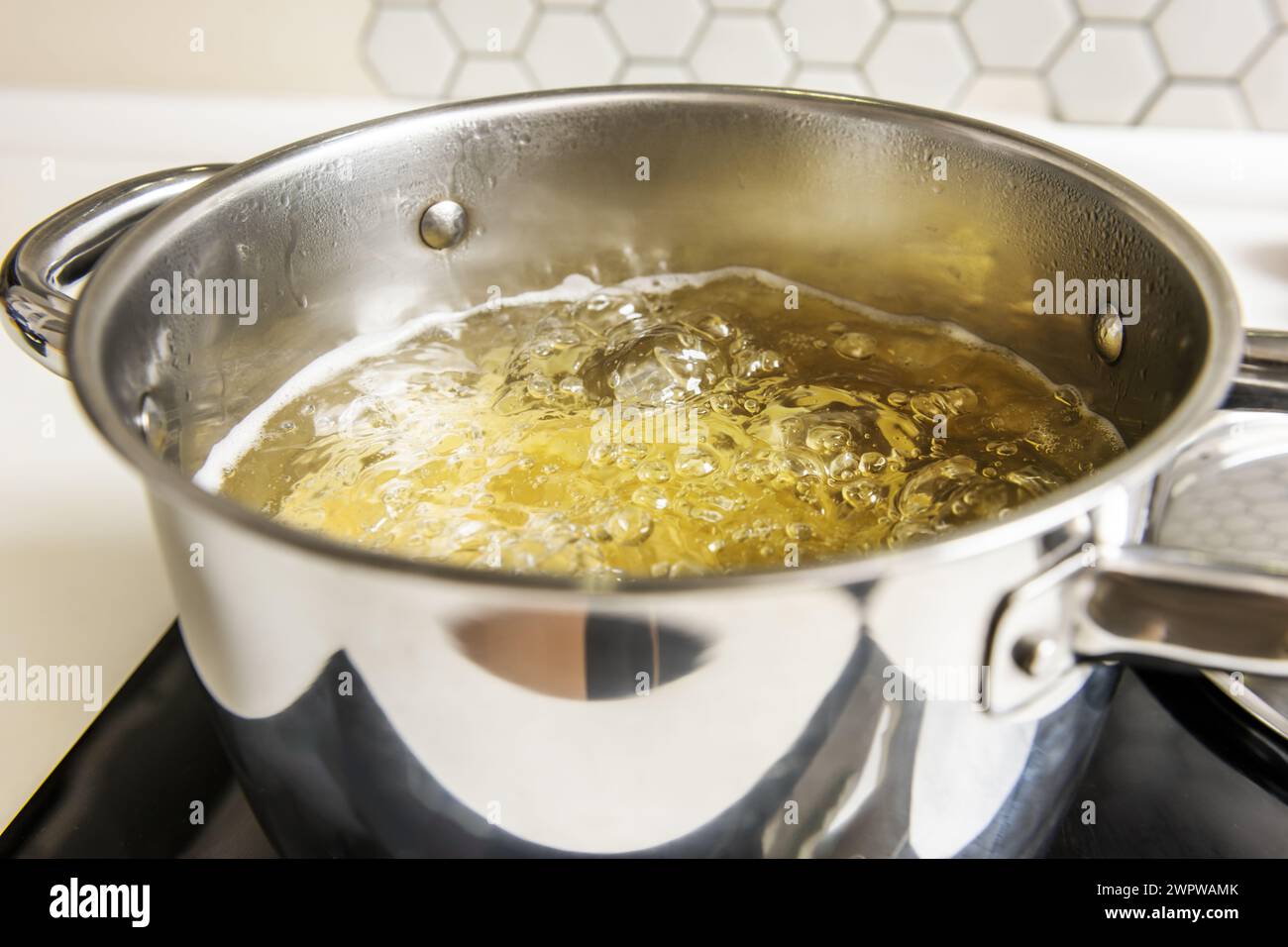 A stainless steel pot filled with boiling water bubbling at 100 degrees Celsius Stock Photo