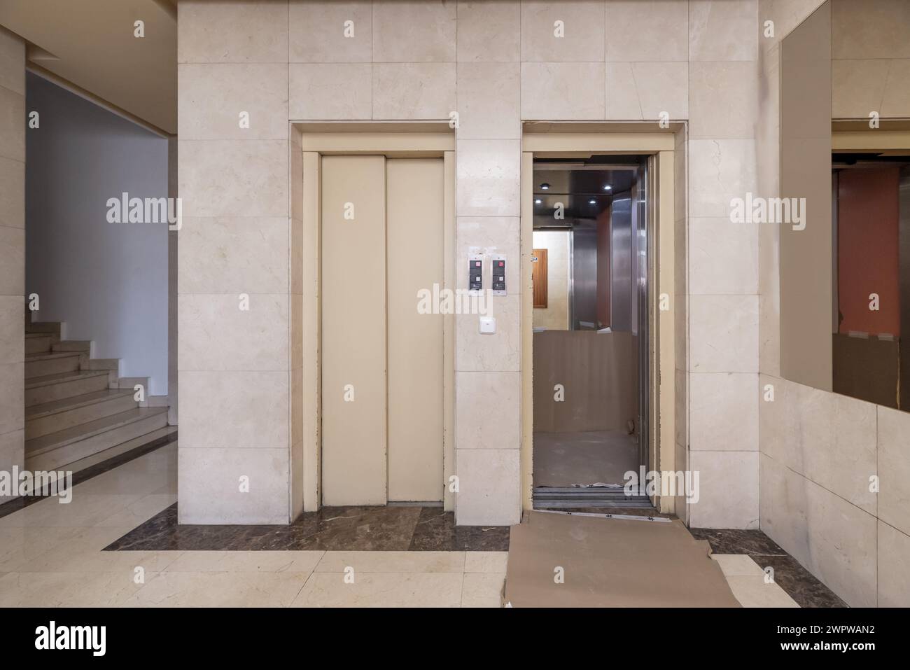 Elevator doors in the portal of a residential house with marble floors next to the stairs Stock Photo