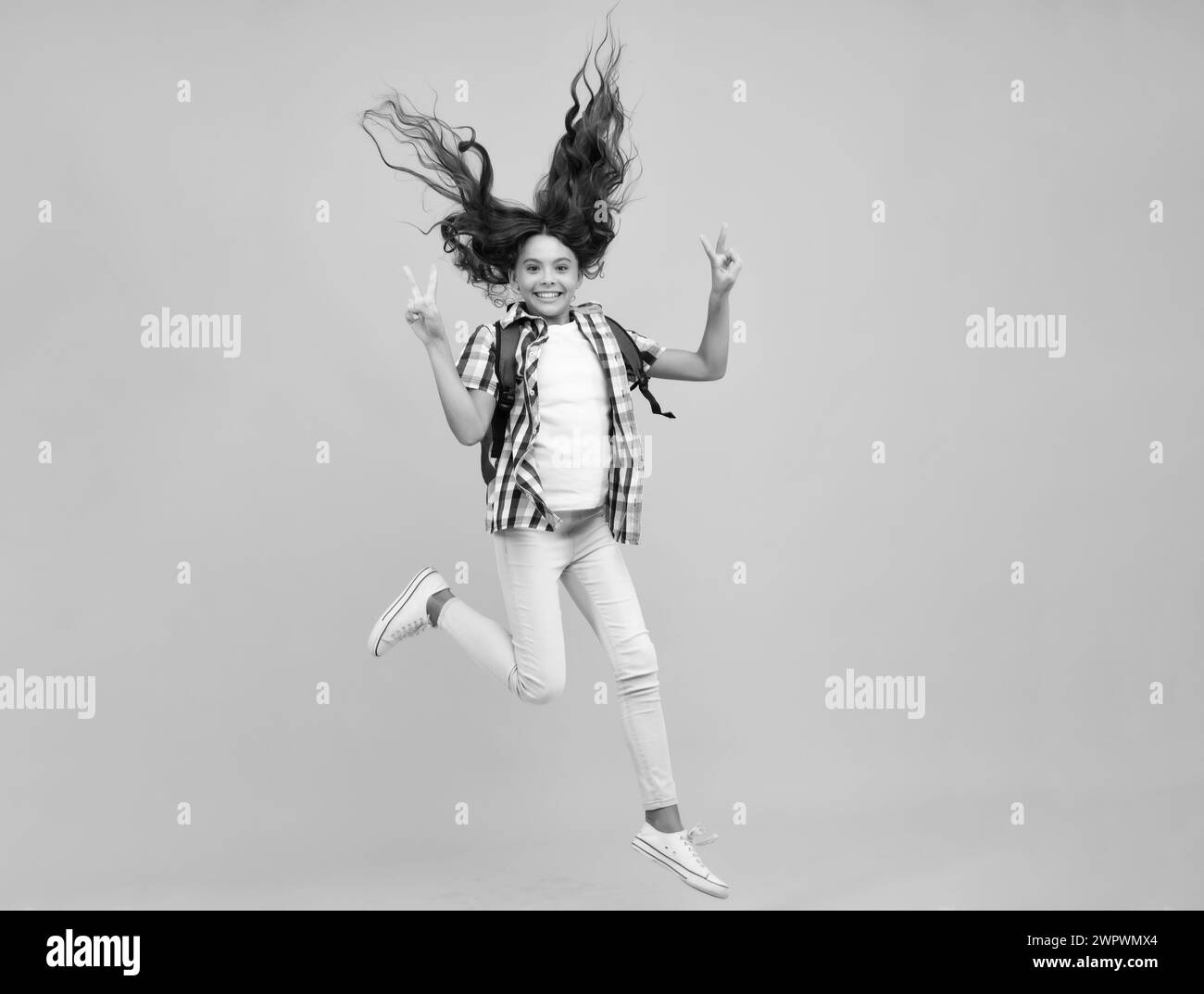 School teen girl in with backpack. Teenager student on isolated background. Run and jump. Kids learning, education, studying and knowledge Stock Photo