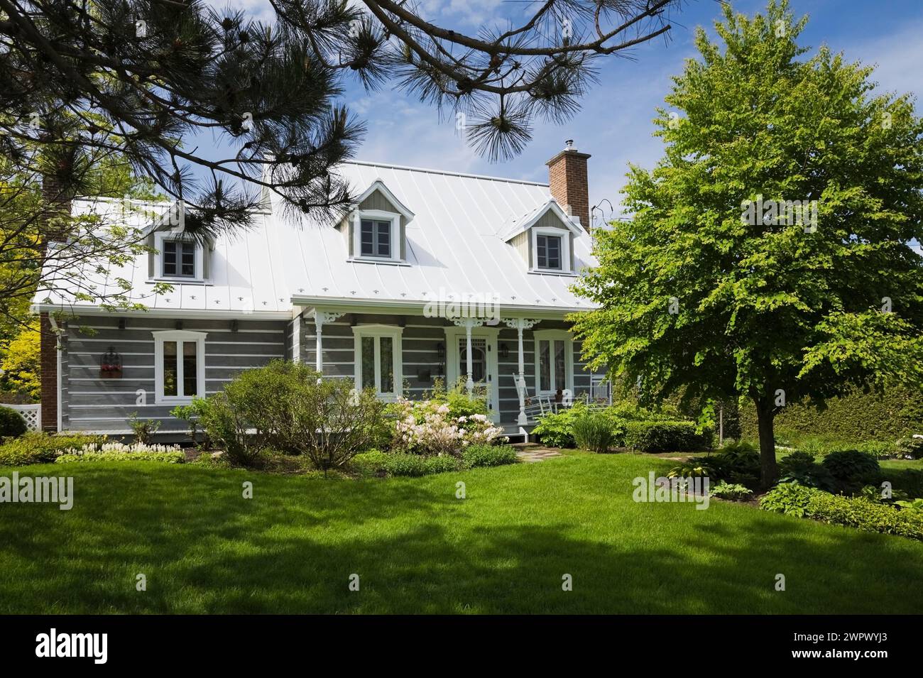 Old log home with landscaped front yard in spring. Stock Photo