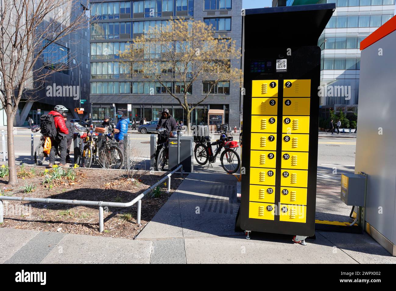 Delivery workers at an E Bike Battery Charging Pilot Study station in Manhattan's Cooper Union Square, New York City, March 8, 2024. Stock Photo