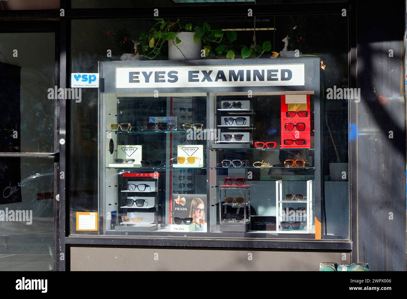 Window display of designer sunglasses and 'Eyes Examined' at an optician, eyeglass store in New York City Stock Photo