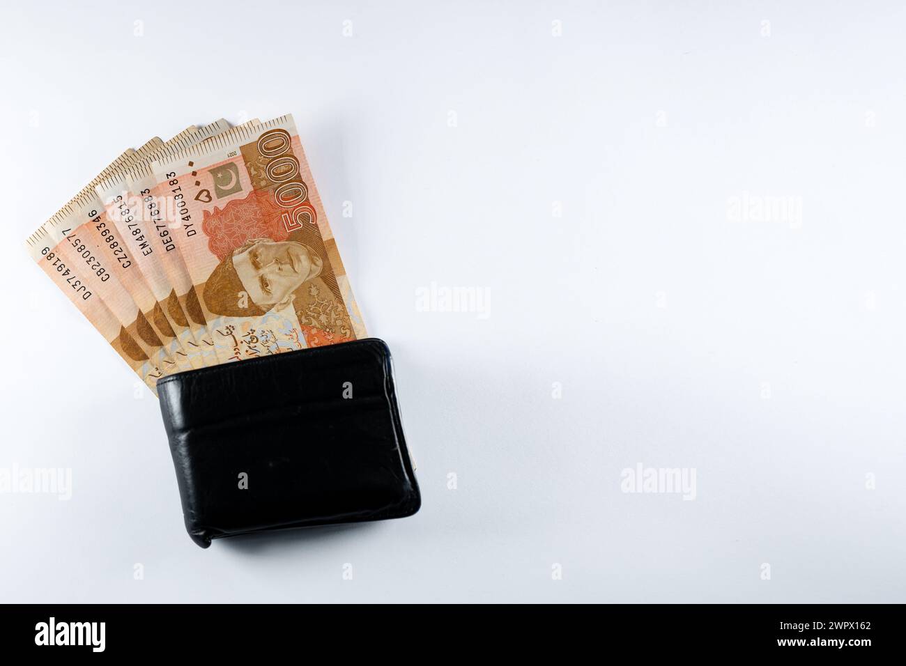 Five thousand 5000 rupee bank notes aligned with a black leather wallet. Pakistan State Bank official currency notes 2024 isolated on white backgroud. Stock Photo