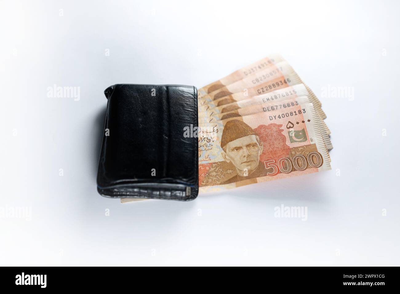 Five thousand 5000 rupee bank notes aligned with a black leather wallet. Pakistan State Bank official currency notes 2024 isolated on white backgroud. Stock Photo