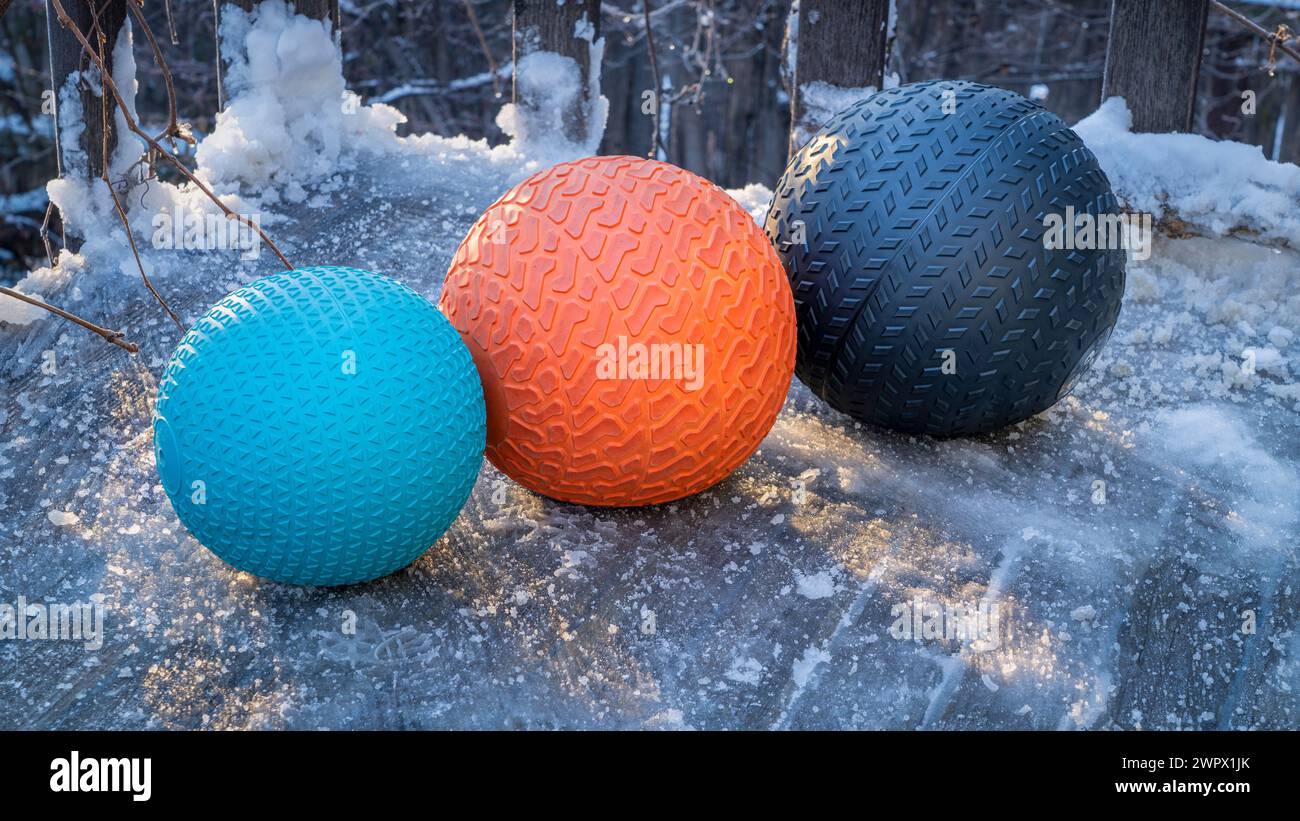 heavy slam balls filled with sand on an icy backyard deck, exercise and functional fitness concept Stock Photo