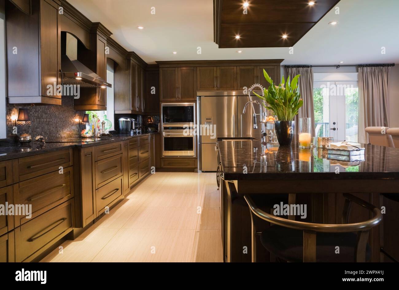 Granite countertop island in spacious kitchen with brown stained wooden ...