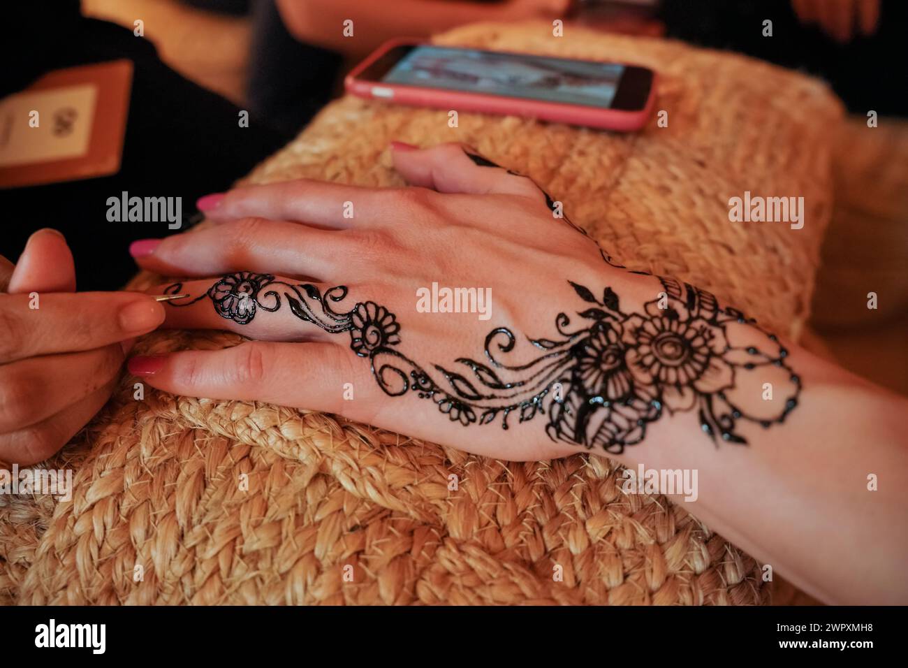 Young woman getting her temporary henna tattoo done, ink still thick