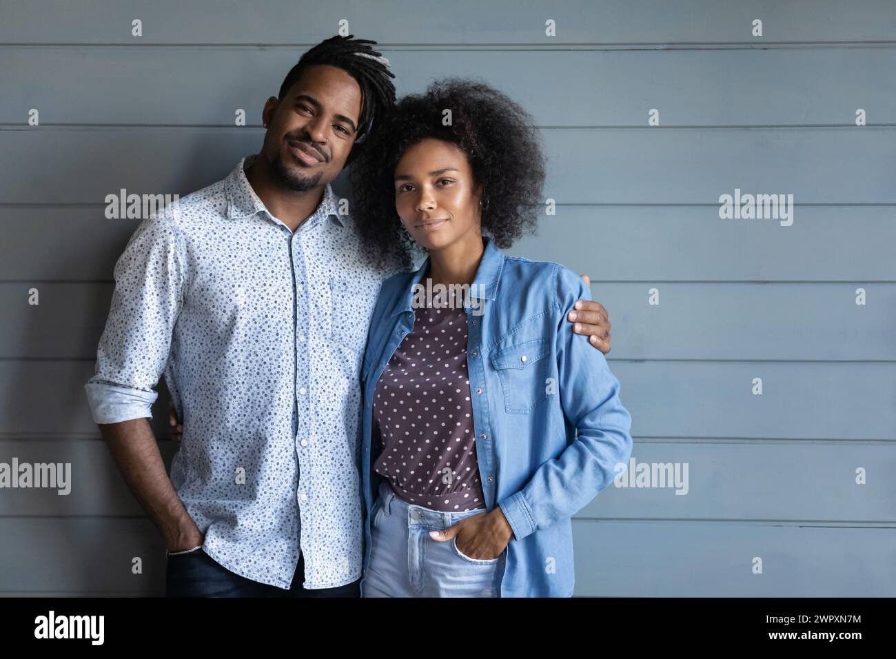 Beautiful African young couple pose on blue wooden wall background ...
