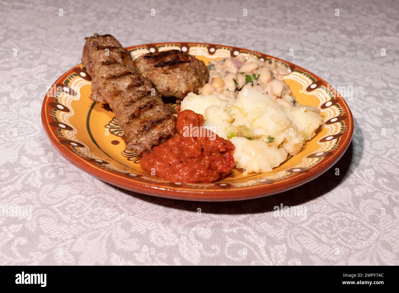 Plate With Traditional Bulgarian Food. Mashed Potato, Vegetable Relish Ljutenica, White Beans, Haricot, Grilled Minced Meat With Spices Kebapche Stock Photo