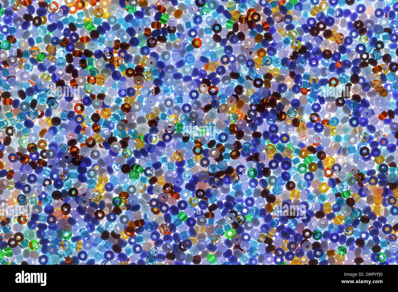 Abstract background made of multi-colored glass beads for embroidery. Multicolored pattern with bottom illumination Stock Photo