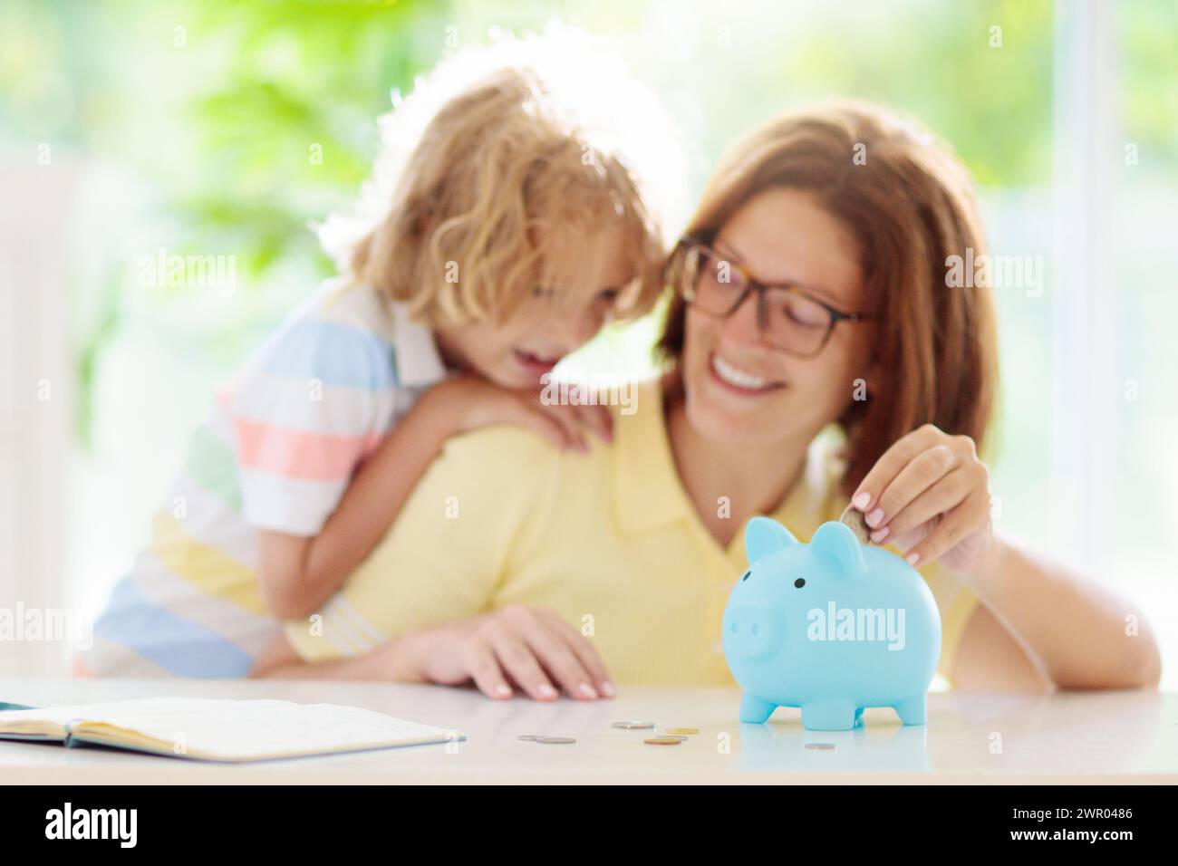 Child putting coin in piggy bank. Kids learn about money. Savings and investment. Little boy saving cash. Wealth growth for young family with children Stock Photo